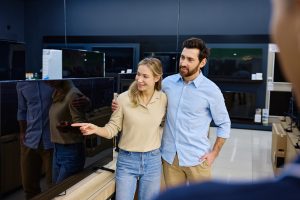 A joyful couple enjoying shopping for a brand new TV at a bustling electronic store